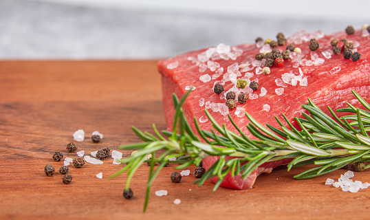 red meat with rosemar and spicery on brown wood background