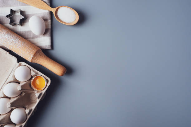 istock Different ingredients and kitchen utensils for making cookies or cupcakes, flat lay, copyspace. Eggs, rolling pin, whisk, flour, cookie molds, layout on a gray background. The concept of home baking 1301706248