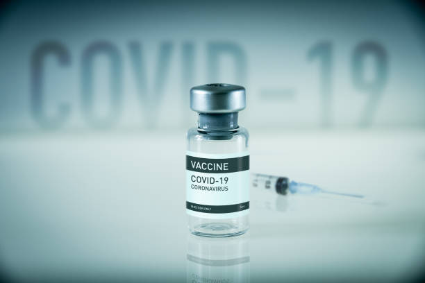 istock Covid-19 vaccine bottle and syringe on a blue background 1301711692