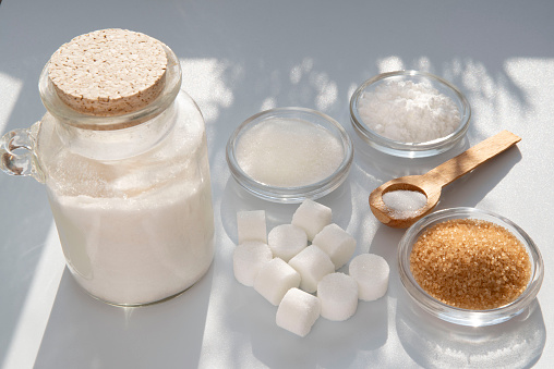 Different kinds of sugars in containers and spoons