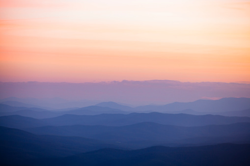 Rolling hills with pastel peach and pink sky at sunset in the mountains