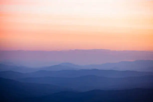 Photo of Rolling hills with pastel peach and pink sky at sunset in the mountains