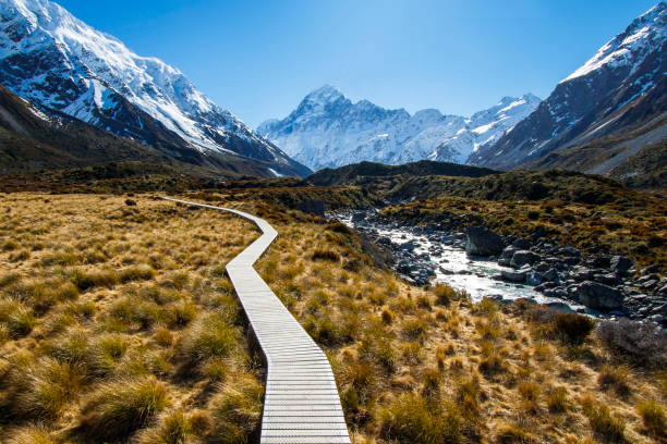 Mountain footpath boardwalk in valley surrounded by snowcapped mountains Mountain footpath boardwalk in valley surrounded by snowcapped mountains with no people on the way to Mount cook, New Zealand mt cook photos stock pictures, royalty-free photos & images