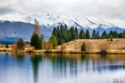 Winter scene of snow capped mountains reflecting off a still lake in New Zealand