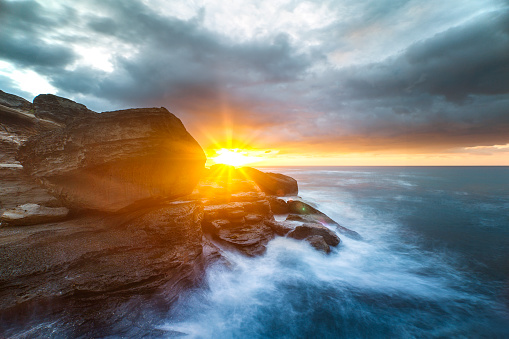 Sunrise and dramatic storm over coast with ocean waves, south coast, NSW, Australia