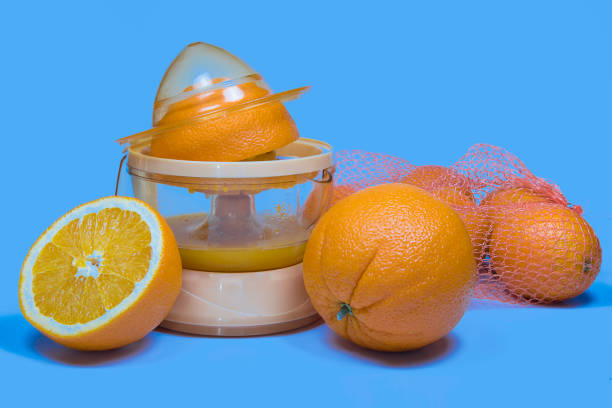 istock Electric press juicer with cut orange isolated on blue background. Manual juice extractor. Juicing oranges. 1301718324