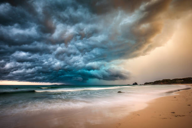 Powerful dramatic storm cell over ocean beach Powerful dramatic storm cell over ocean beach with golden light, Australia beach storm clouds stock pictures, royalty-free photos & images
