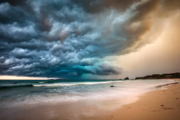 Powerful dramatic storm cell over ocean beach with golden light, Australia