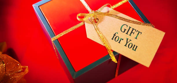 istock Gift for you - text on gift box label, red background, top view. 1301724370