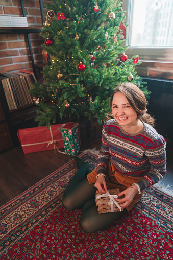 Young Caucasian woman wrapping presents under  the Christmas tree
