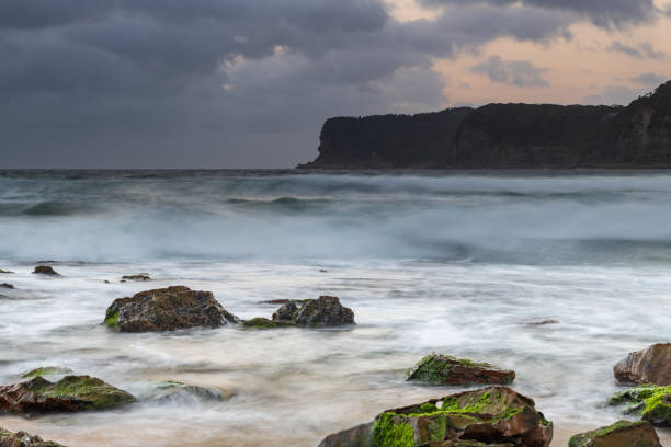 istock Grey clouds and rocky foreground overcast sunrise at the beach 1301728373