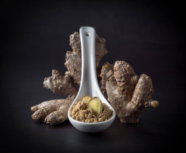 istock Ginger root and ginger powder in a spoon on black background, closeup. 1301729767
