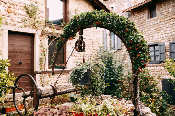istock Old wooden stone well with red flower arch and ivy in Perouges, France 1301733021