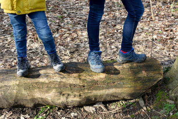 하이킹 부츠를 신고 어린 소년의 발과 다리를 가까이서 나무 줄기 위에 서 있었습니다. - healthy lifestyle nature sports shoe childhood 뉴스 사진 이미지