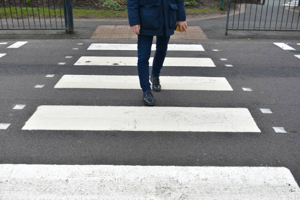 close up of mans feet and legs, walking along a zebra crossing, - single lane road imagens e fotografias de stock