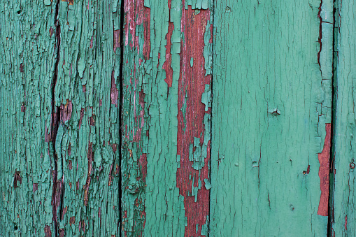 Wood texture with green and red flaked cracked paint on weathered surface