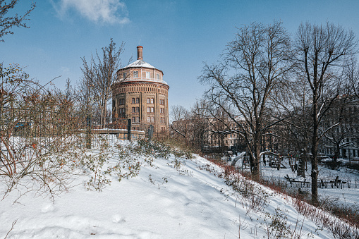 old water tower on snow capped hill in Berlin Prenzlauer Berg under blue sky of a sunny winter day