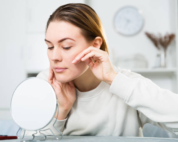istock Smiling female is looking on her skin in the mirror 1301739496