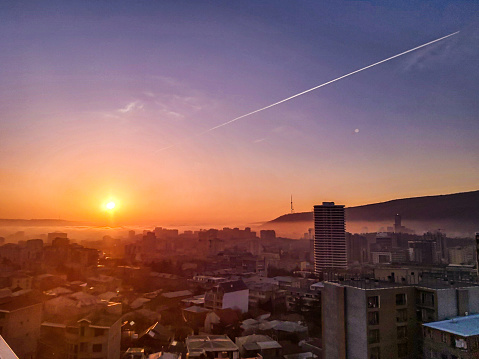 Dramatic sunrise over Tbilisi city centra with fog and red sun going up over the skyline