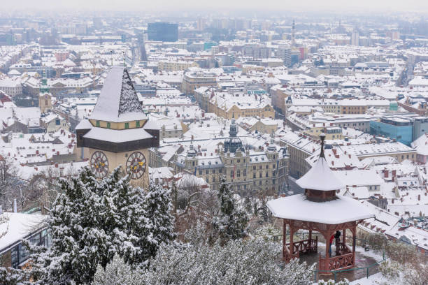 знаменитая башня с часами на холме шлосберг и исторические здания на крышах со снегом, в граце, регионе стирия, австрия, в зимний день - graz clock tower clock austria стоковые фото и изоб�ражения