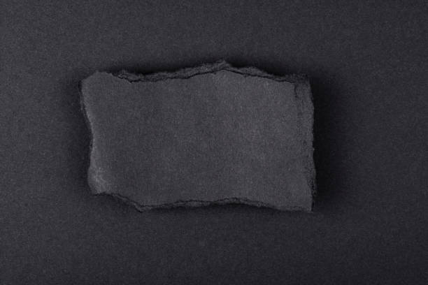 istock Torn sheet of black paper on a black background. 1301741965