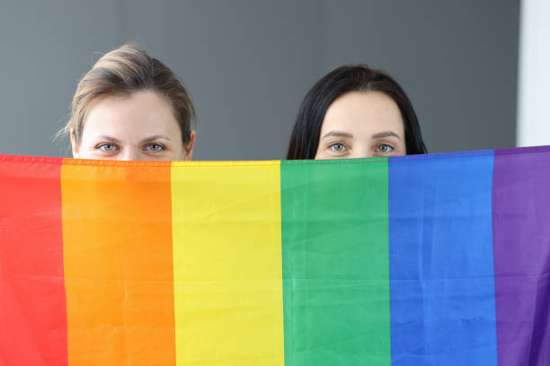 istock Two women hold lgbt flag in front of them 1301743105