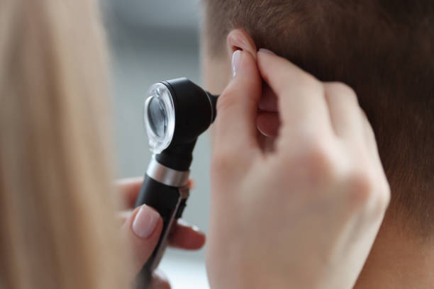 otorrinolaringologista puxando a orelha com a mão e olhando para ela com otoscópio de perto - aparelho auditivo - fotografias e filmes do acervo
