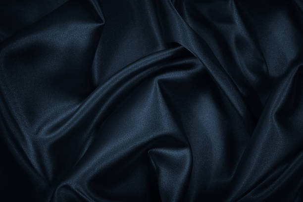 istock Black blue abstract background. Dark blue silk satin texture background. Beautiful wavy soft folds on the surface of the fabric. 1301745044
