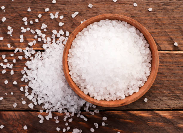 Salt in a plate and sprinkled on a wooden background. Salt in a plate and sprinkled on a wooden background. The view from top salt mineral stock pictures, royalty-free photos & images