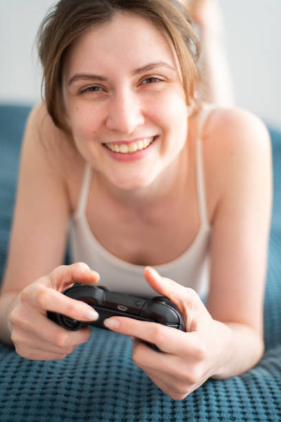 istock Smiling millennial woman enthusiastically plays a game using the controller from the console. Vivid emotions from fear on the faces of the girls from the game online 1301747120
