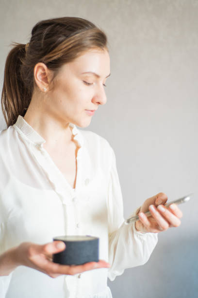 A young woman connects a voice assistant in a portable device to her phone synchronizing them.