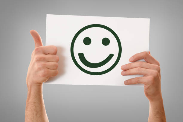 istock Two hands holding white sheet with happy face emoticon isolated 1301748752