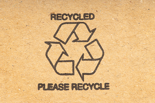 Recycle symbol on brown recycled cardboard background. Close up