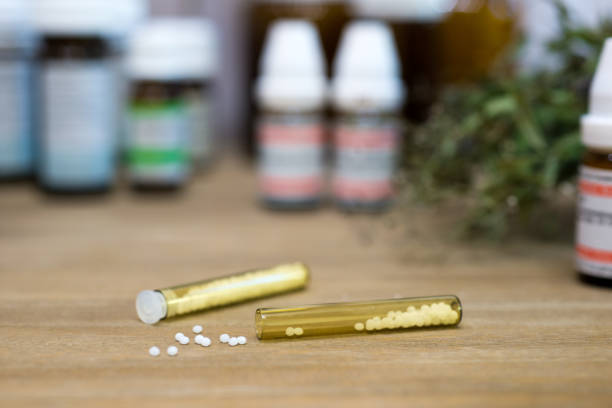 istock Homeopathy globules and vials on a table with old books 1301749380