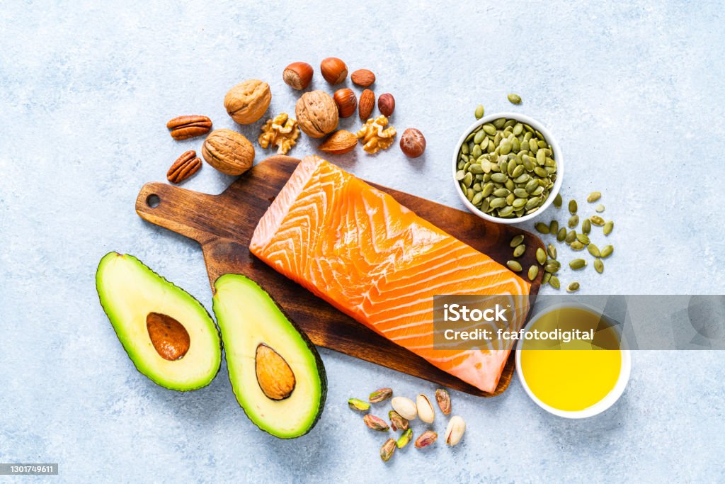 Food with high content of healthy fats. Overhead view. Healthy eating for well balanced diet and heart care: overhead view of a group of food rich in healthy fats. The composition includes salmon, avocado, extra virgin olive oil, nuts and seeds like walnut, almonds, pecan, hazelnuts, pistachio and pumpkin seeds. High resolution 42Mp studio digital capture taken with SONY A7rII and Zeiss Batis 40mm F2.0 CF lens Healthy Eating Stock Photo