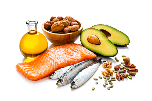 Healthy eating for well balanced diet and heart care: close up view of a group of food rich in healthy fats isolated on white background. The composition includes salmon, sardines, avocado, extra virgin olive oil, nuts and seeds like walnut, almonds, pecan, hazelnuts, pistachio and pumpkin seeds. High resolution 42Mp studio digital capture taken with SONY A7rII and Zeiss Batis 40mm F2.0 CF lens