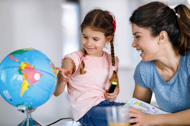 Learning about the Globe during home schooling! Happy single mother teaching her daughter about the Globe during home schooling due to coronavirus epidemic. elementary student pointing stock pictures, royalty-free photos & images
