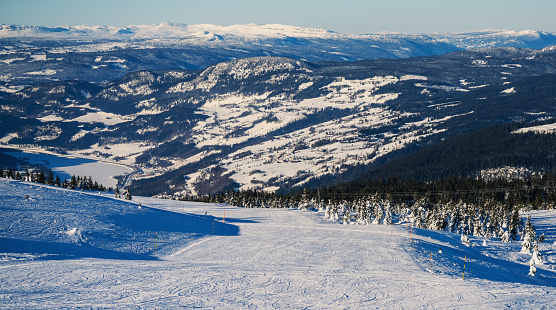 Empty downhill ski slopes at a popular ski resort. View over a snow covered valley.