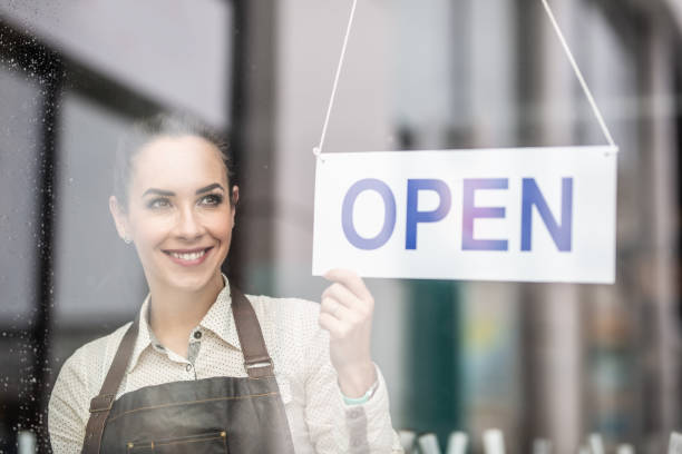 istock Smiling beautiful waitress turning the sign open  on a restaurant or a bar. 1301751278