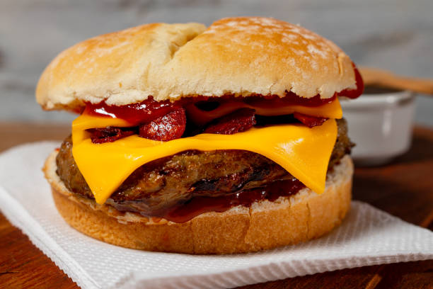 pyszny hamburger z boczkiem i serem cheddar na domowym chlebie z nasionami i ketchupem na drewnianej powierzchni i rustykalnym tle. - bacon cheeseburger zdjęcia i obrazy z banku zdjęć