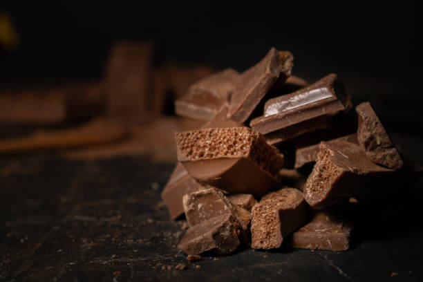 istock Different pieces of dark chocolate and cocoa powder on a dark surface. Space for text 1301752657