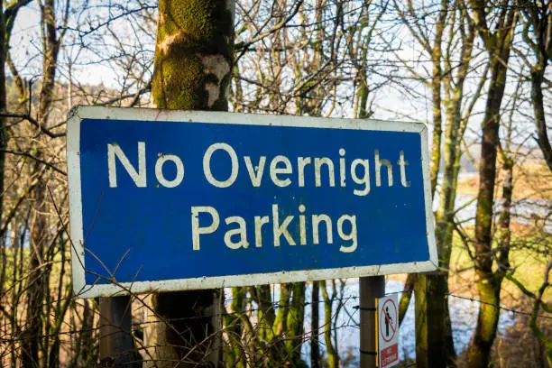 Photo of Blue sign warning of no overnight parking beside a lake or loch in Scotland