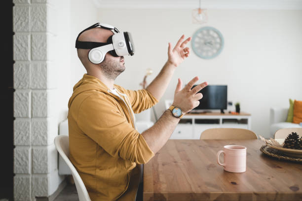 Young man touching the air using virtual reality glasses at his home. high tech vr glasses. stock photo