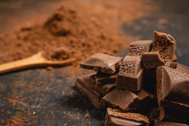istock Different pieces of dark chocolate and cocoa powder on a dark surface. Space for text 1301753089