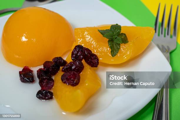 Delicious Peaches In Syrup In A Glass Bowl On A Colored Surface And Some Cranberries Stock Photo - Download Image Now