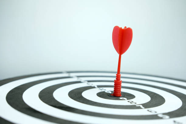 istock Wooden dartboard with red arrow on grey background. 1301756151