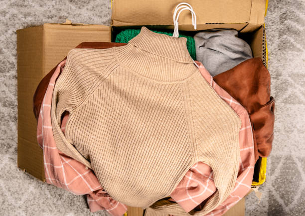 Top view at clothes in cardboard box Clothes for clothing swap. Concept of waste problem in fashion industry. clothing donation stock pictures, royalty-free photos & images