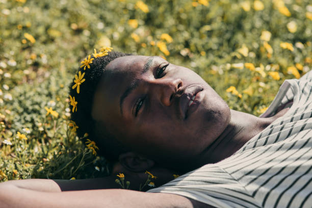 istock A young African man with a flower crown lying in the grass. 1301756708