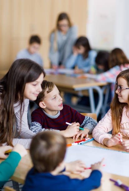 istock Group of happy elementary students drawing something in the classroom 1301757995