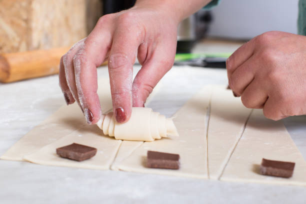 istock Make bakery sweets at home. Making croissants with chocolate. Hands with puff pastry 1301758846